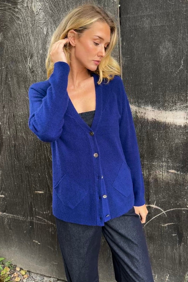 model wearing zola french blue cashmere cardigan against a textured black wall