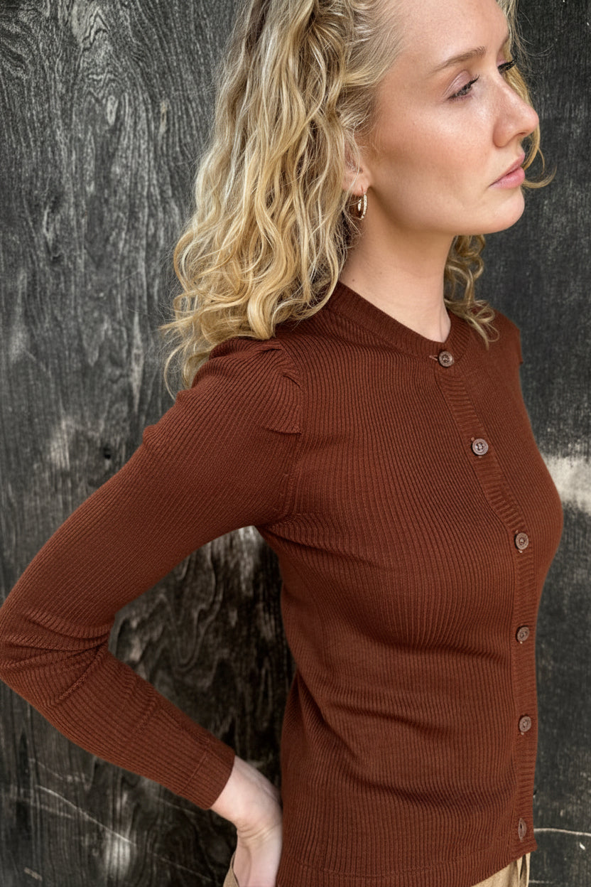 Woman wearing a brown ribbed sweater against a textured black background