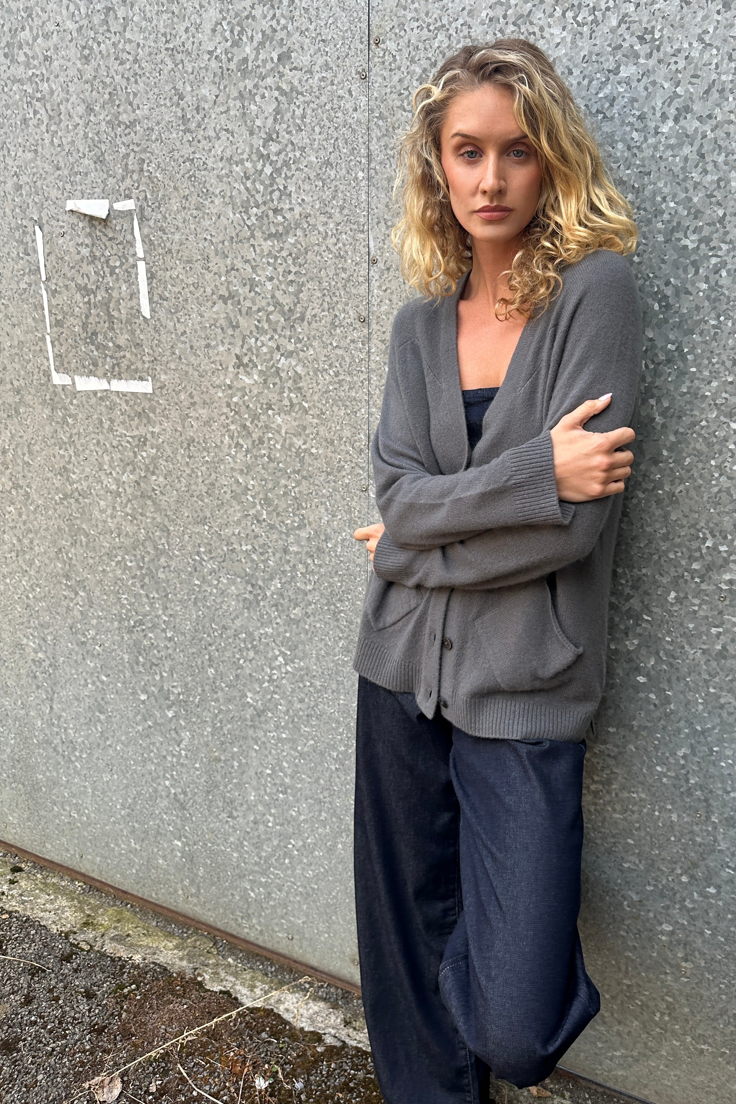 model wearing a Zola gray cardigan grey cashmere against a textured