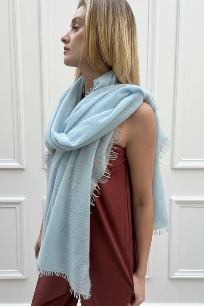 Woman wearing a light blue scarf against a white paneled wall