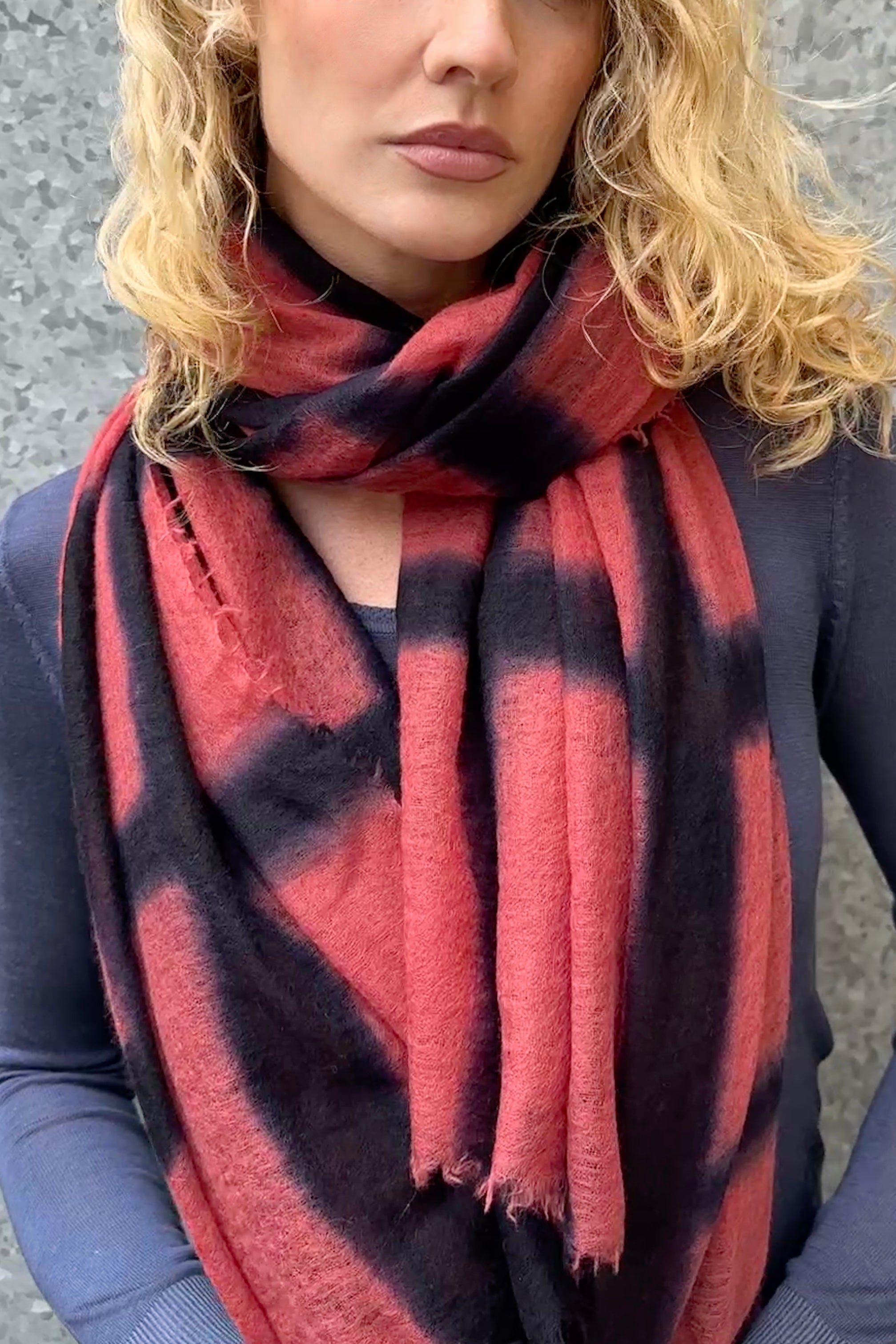 Person wearing a red and black checkered scarf against a gray background