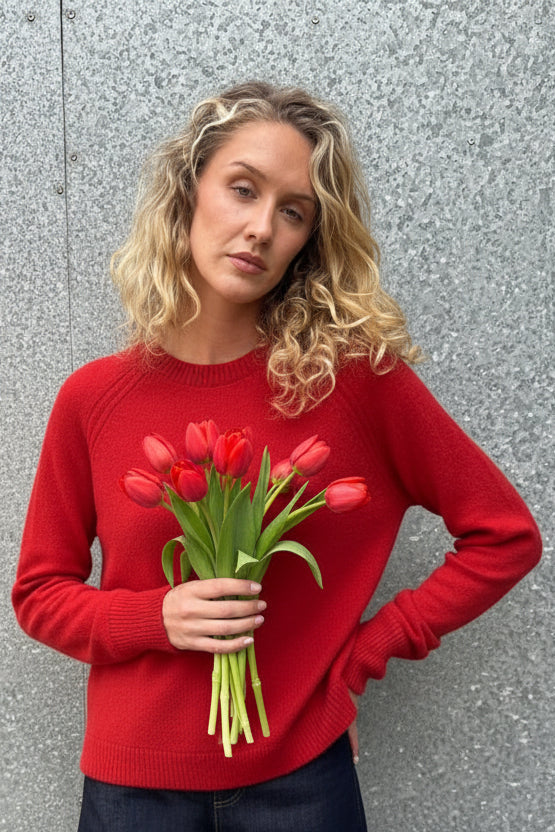 Woman wearing a red sweater against a textured gray wall
