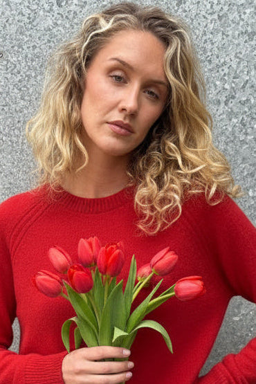 Woman wearing a red sweater against a textured gray wall