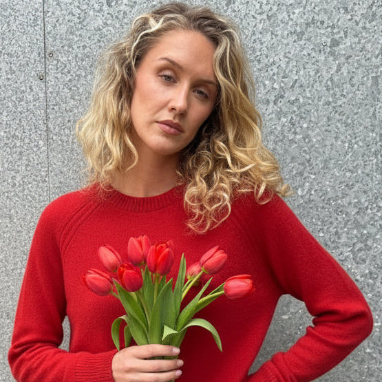 Woman wearing a red sweater against a textured gray wall
