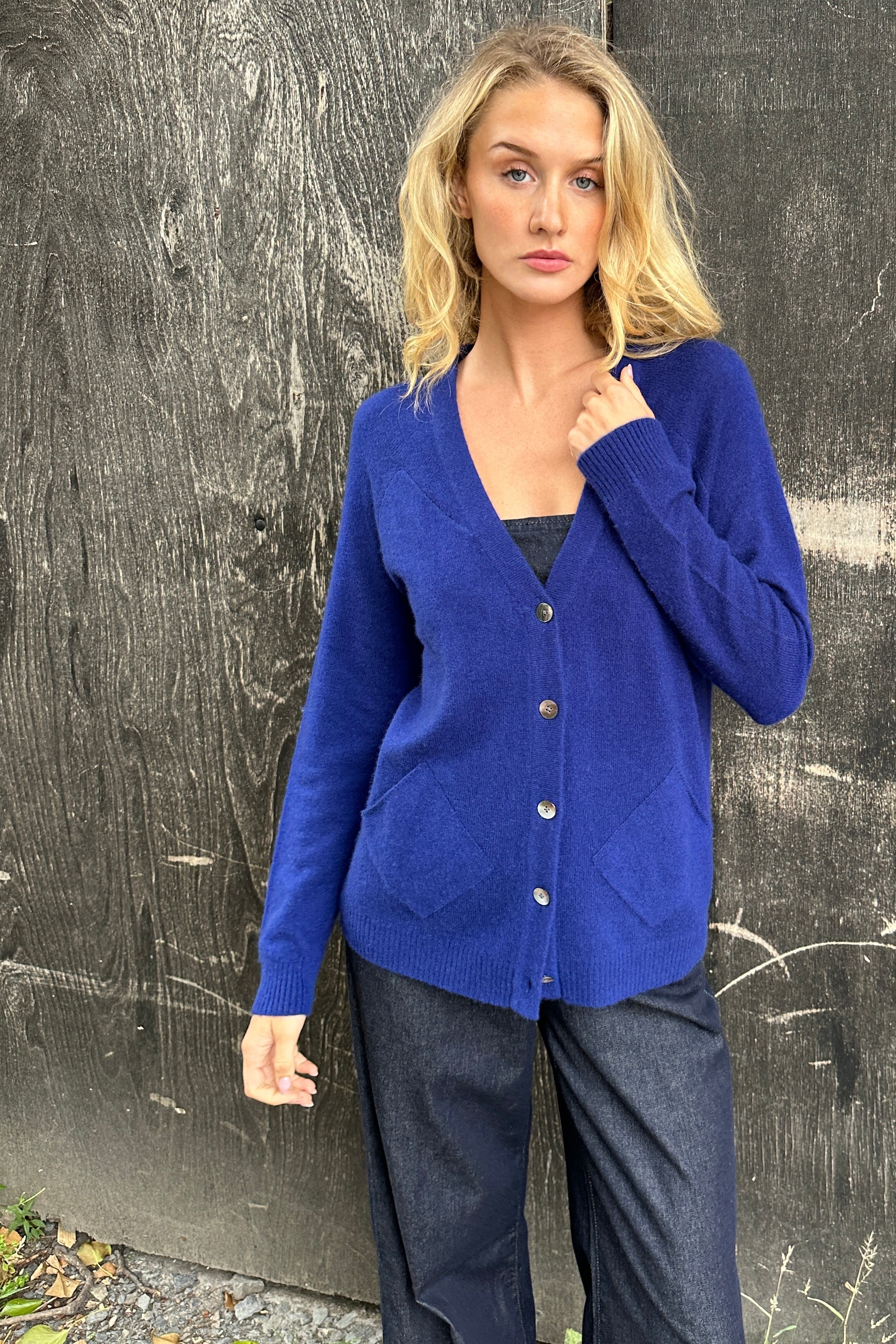 model wearing zola french blue cashmere cardigan against a textured black wall
