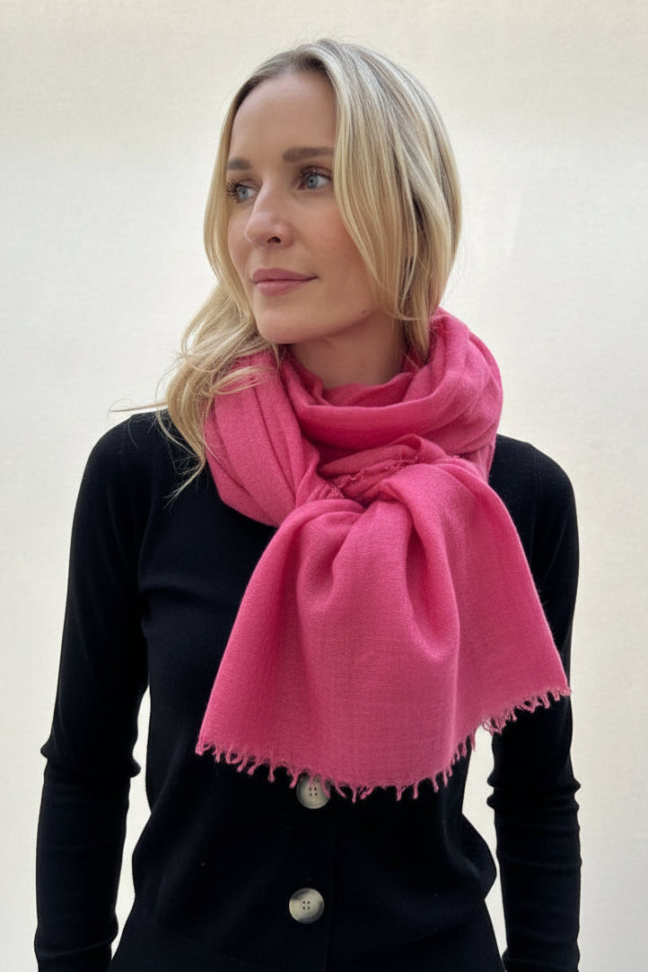 Woman wearing a pink scarf and black top against a white background