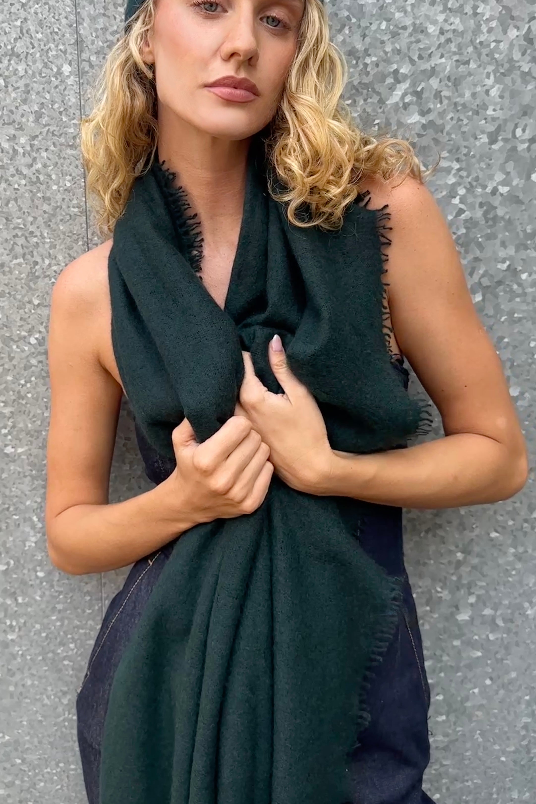 Woman wearing a dark green eighty cashmere scarf against a gray background