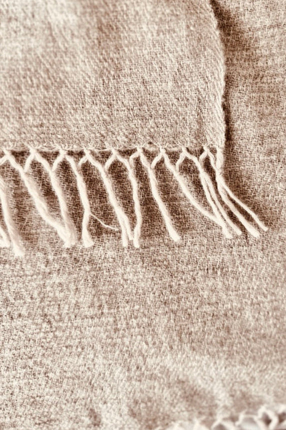 Close-up of a beige cashmere woven fabric with fringed edge