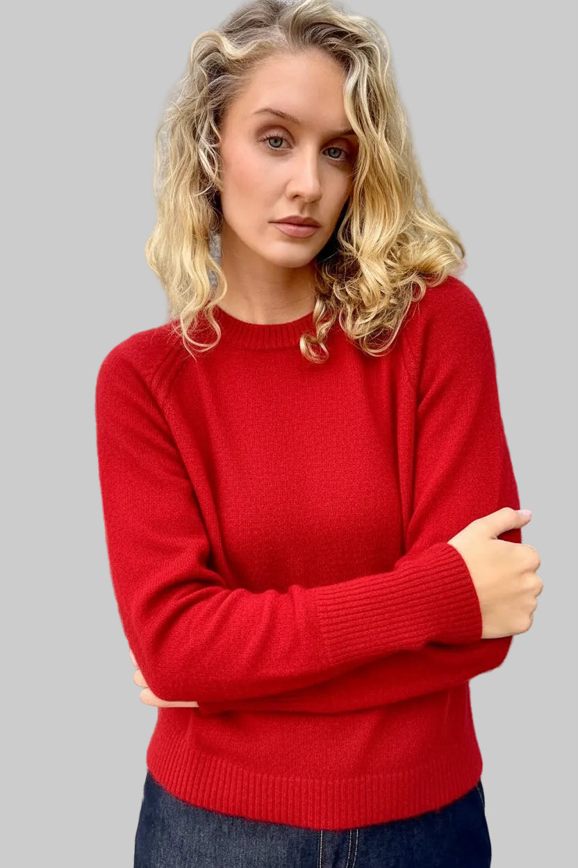Woman wearing a red sweater against a textured wall