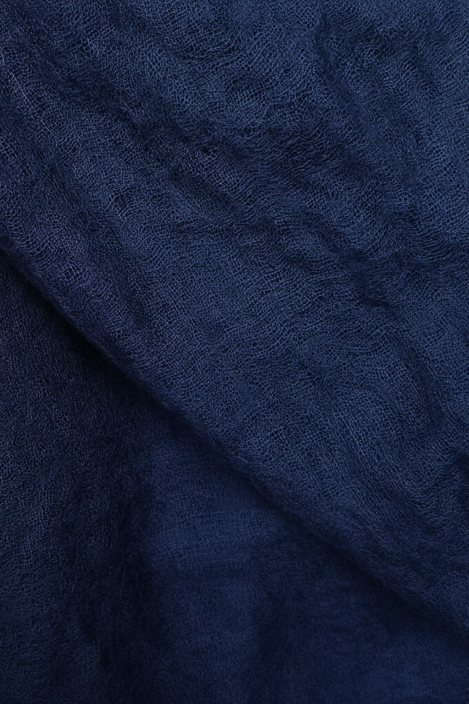 A close-up of dark navy blue textured fabric with a soft, slightly crinkled surface and gentle folds.