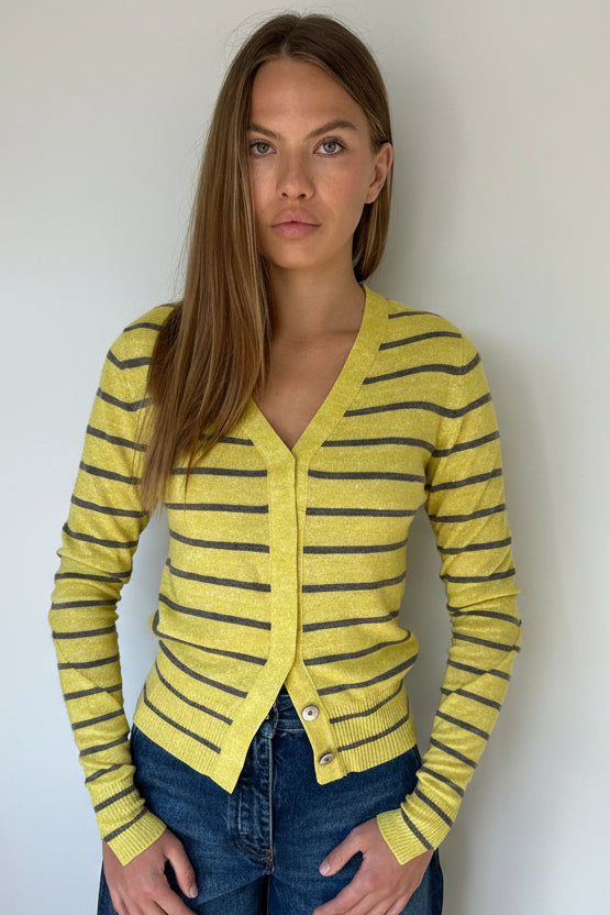 Woman wearing a yellow and black striped cardigan against a white background
