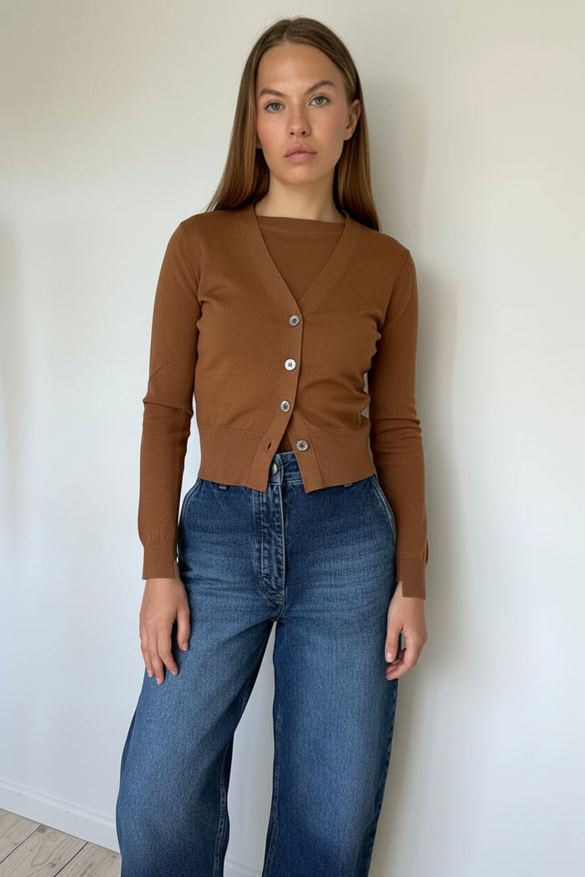 Person wearing a brown cardigan and blue jeans on a white background