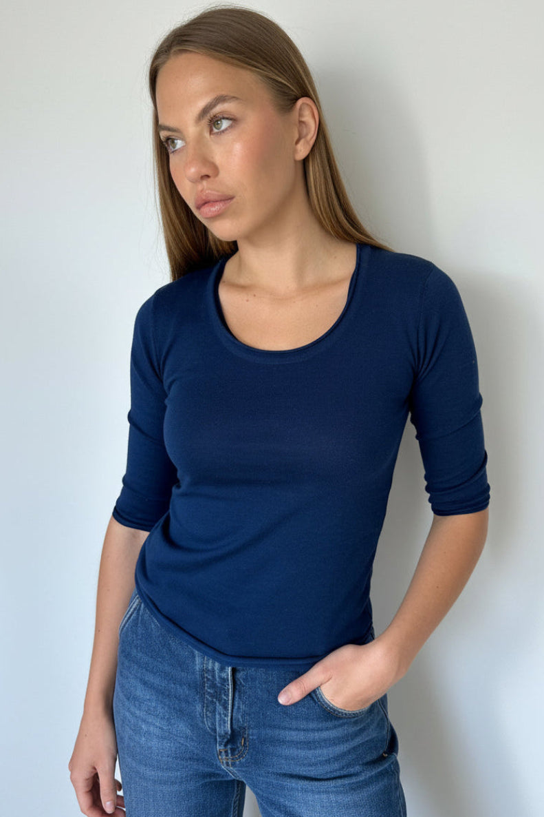 Woman wearing a blue shirt and jeans against a plain background