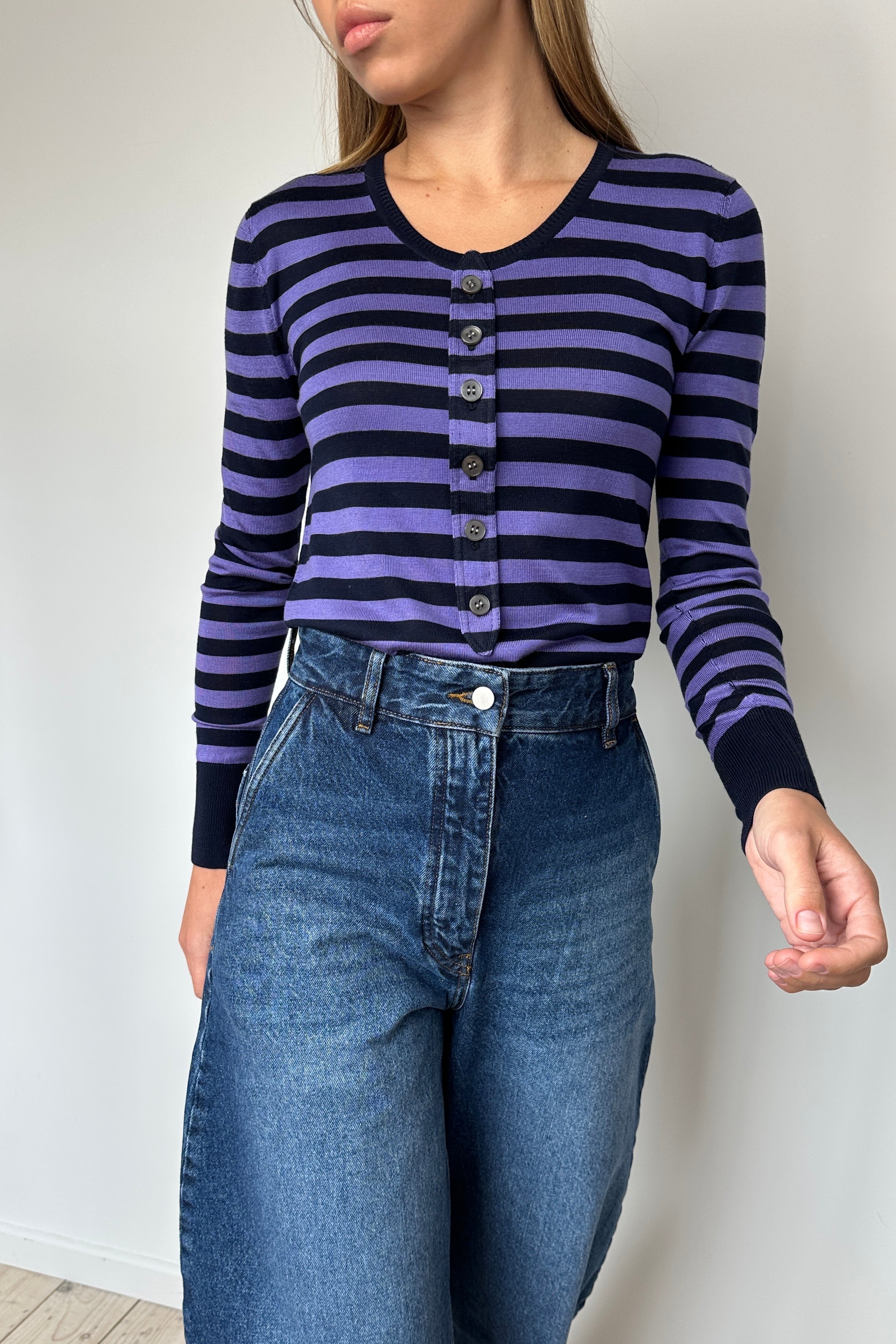 Person wearing a striped cardigan and jeans against a plain background