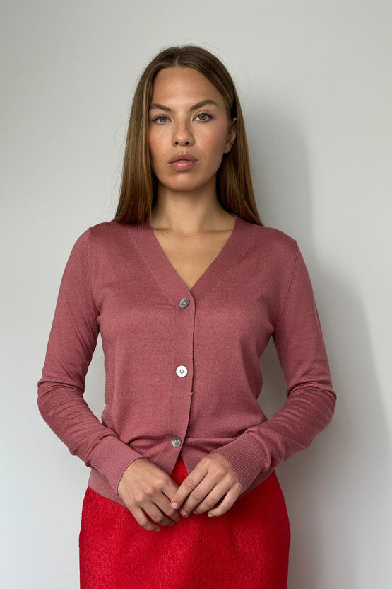 Woman wearing a pink cardigan and red skirt against a plain background