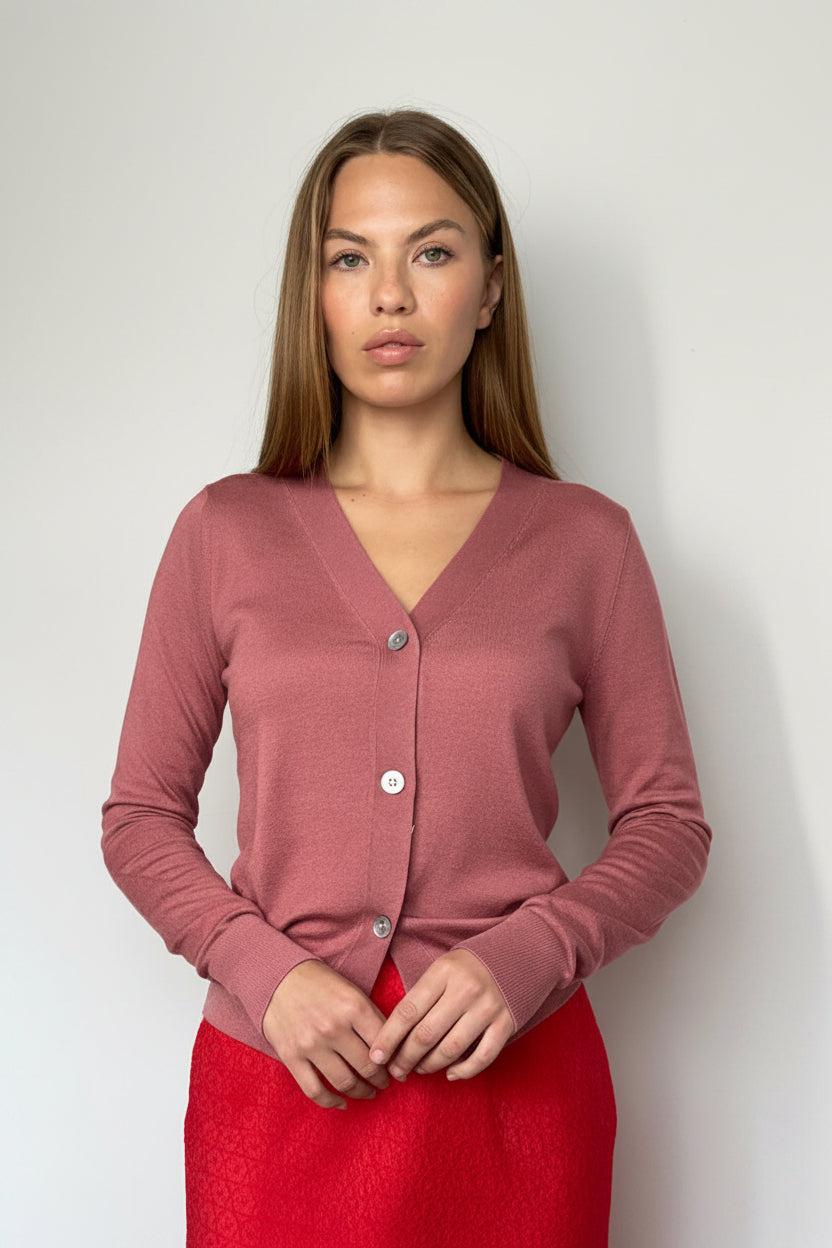 Woman wearing a pink cardigan and red skirt against a plain background
