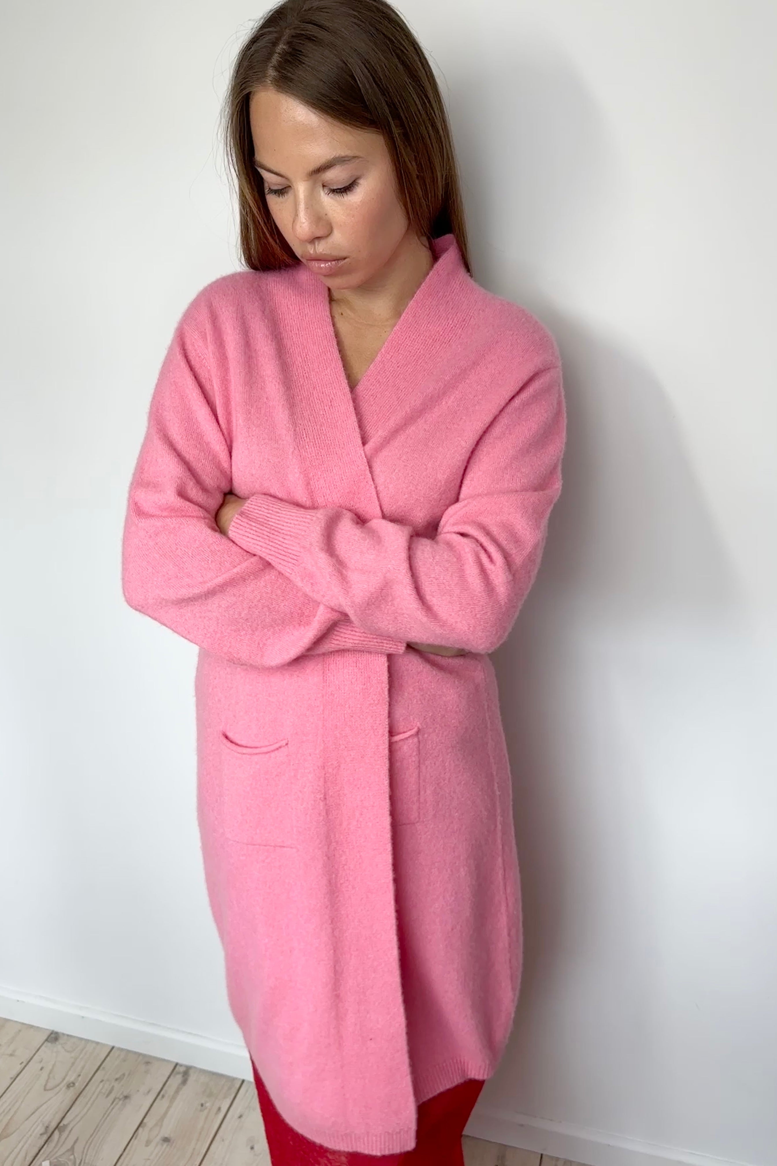 Woman wearing a pink robe against a white wall