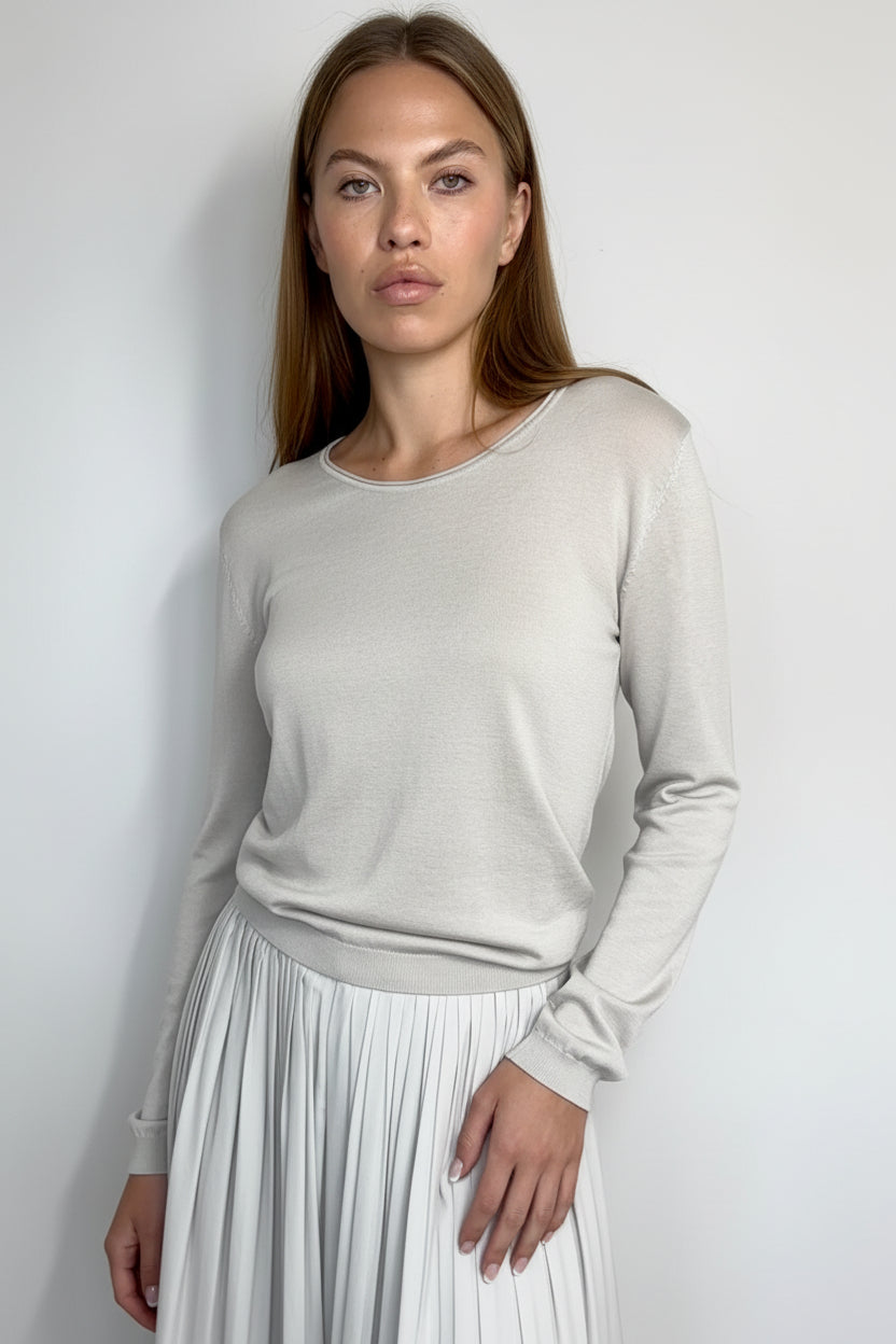 Woman wearing a light gray sweater against a plain background