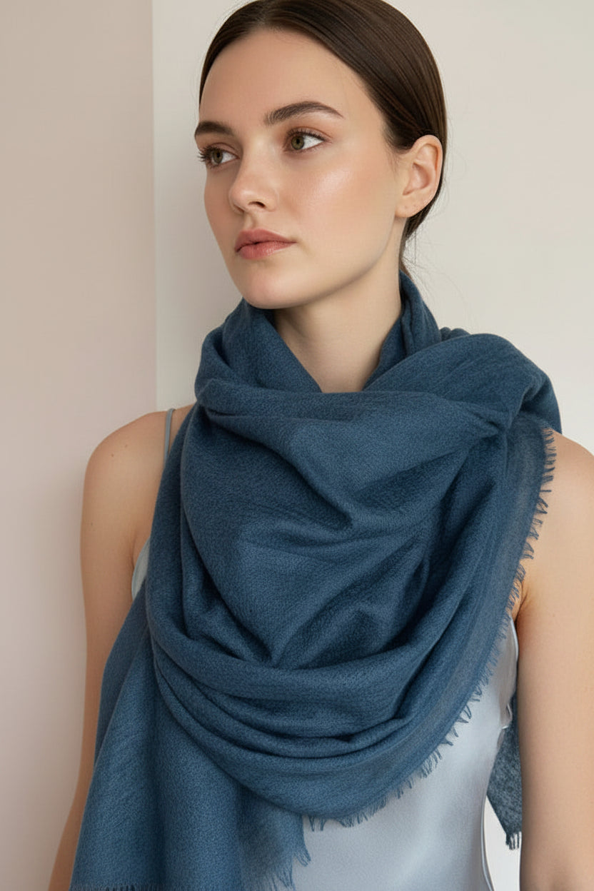 Woman wearing a teal green /blue scarf against a neutral background