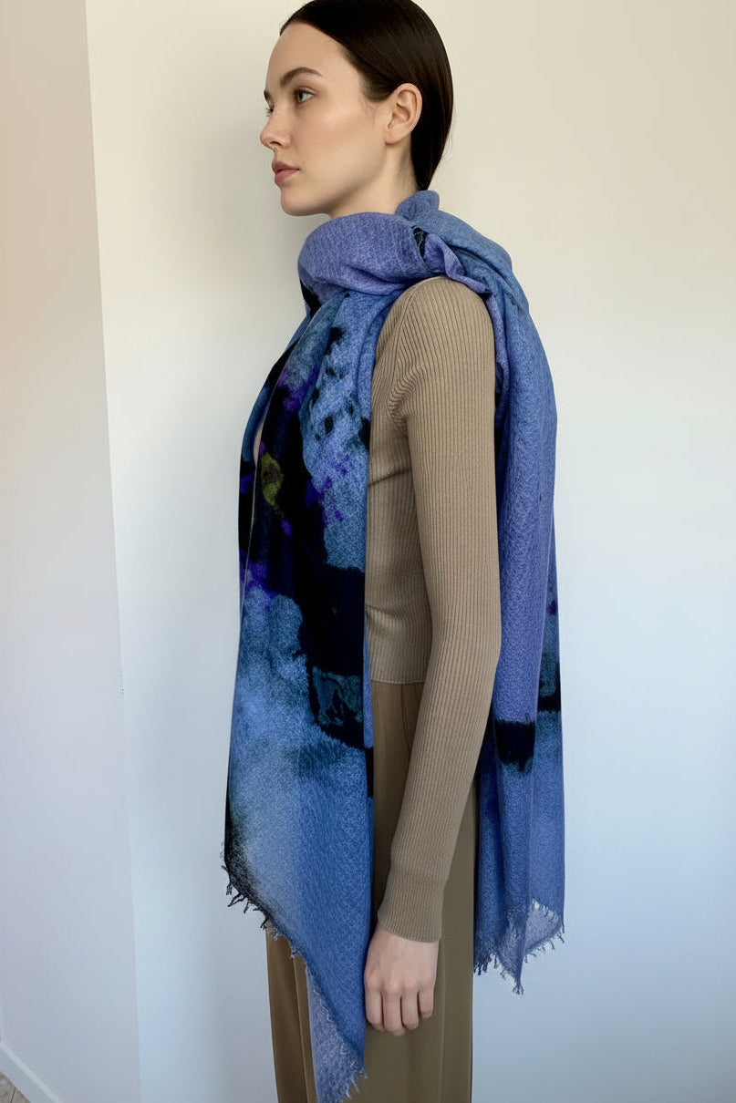 Woman wearing a blue scarf with a colorful pattern against a plain background