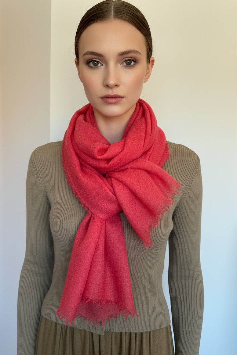 Woman wearing a bright pink scarf against a plain background
