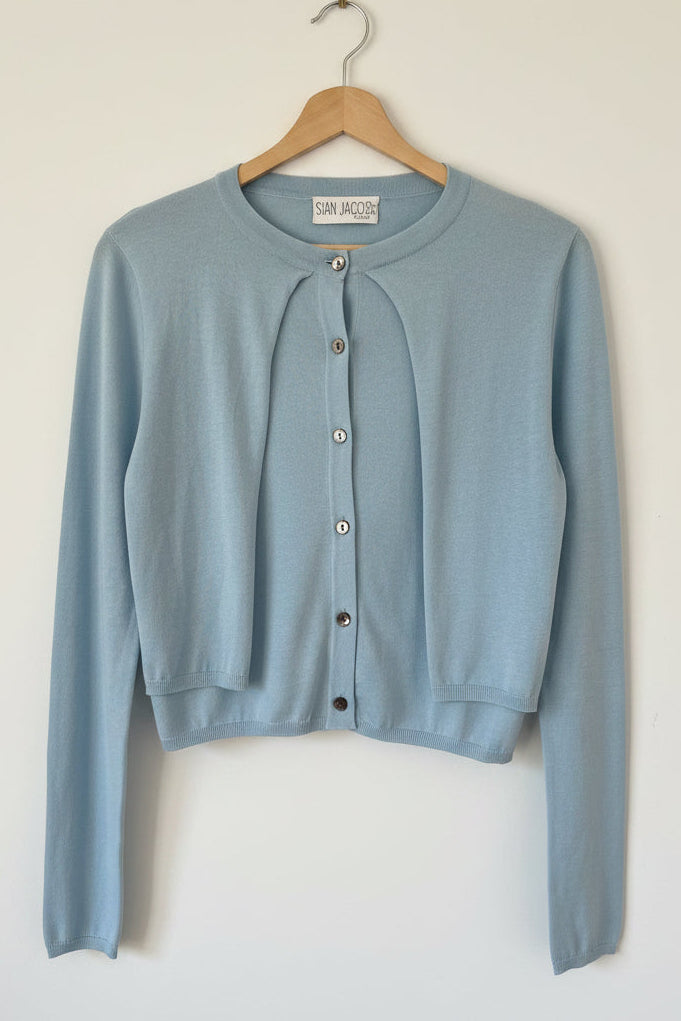 Light blue cardigan on a hanger with a blurred background