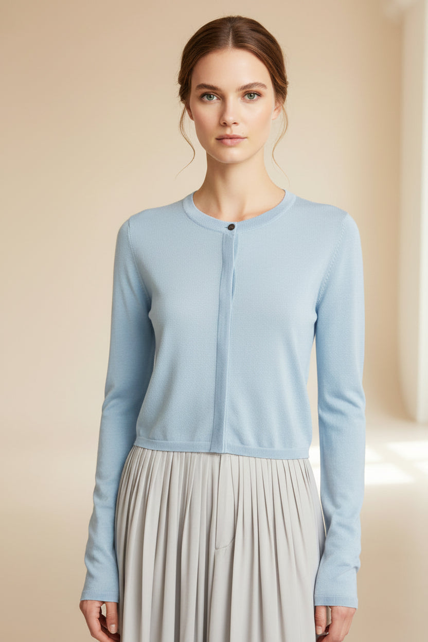 model wearing a light blue jacket over a pleated dress against a plain background
