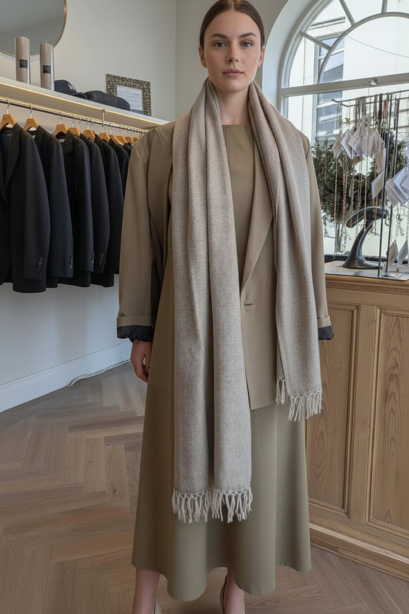 Woman wearing a beige coat and scarf in a clothing store.