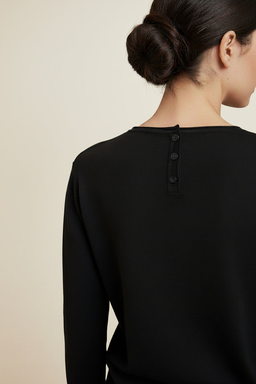 Black long-sleeve shirt on a mannequin against a white wall.