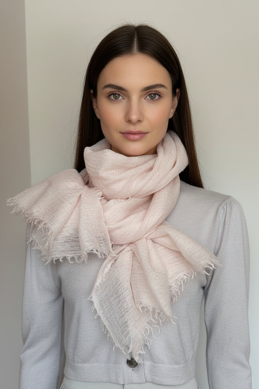 Woman wearing a light pink scarf against a plain background