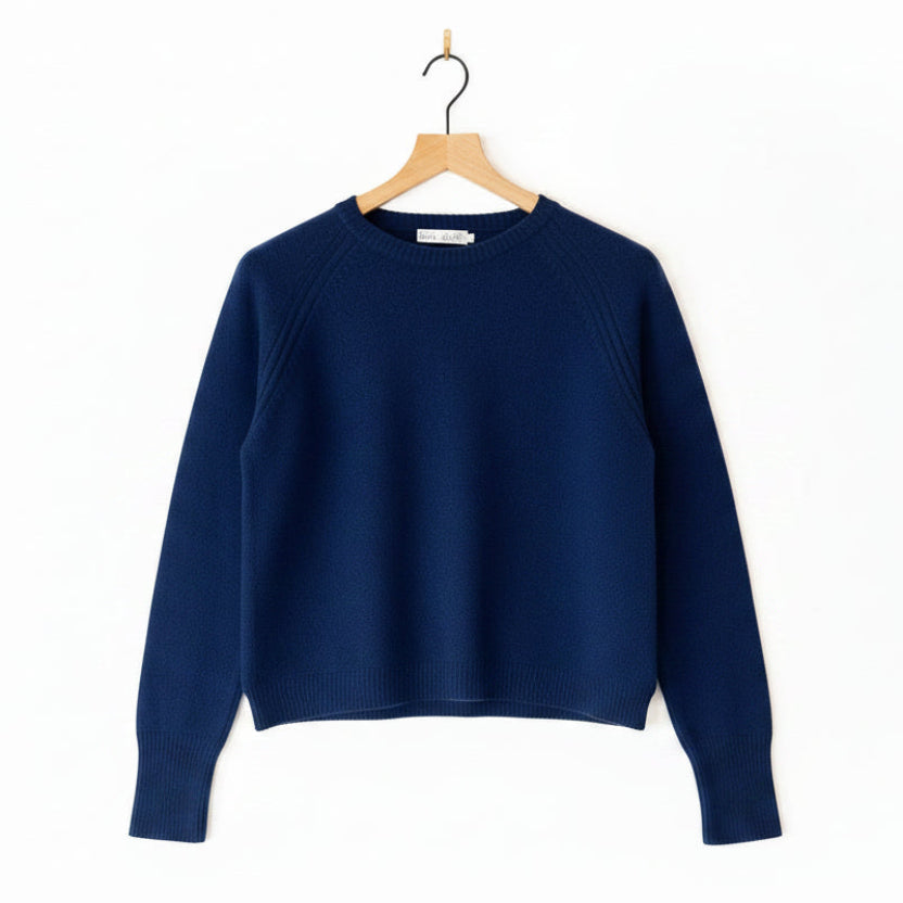 Navy blue sweater on a wooden hanger against a white background