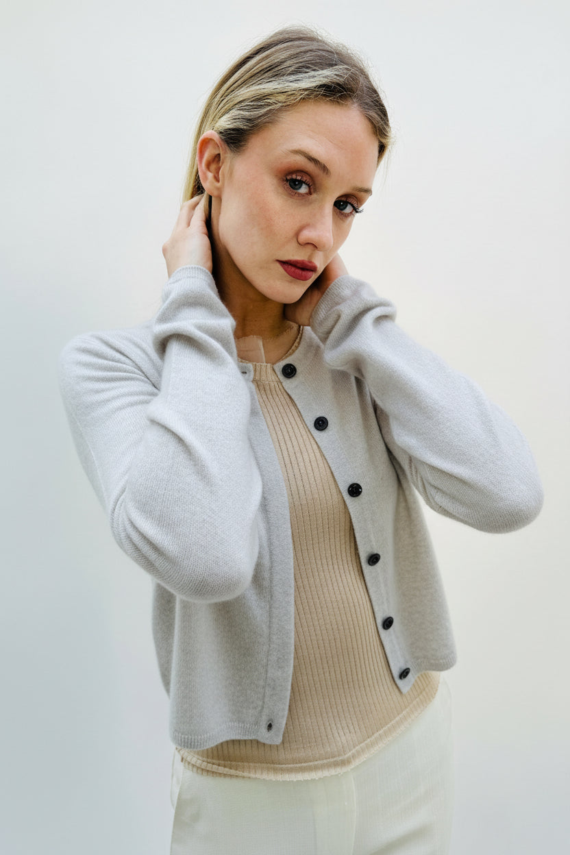 Woman wearing a light gray cardigan over a beige sweater against a white background