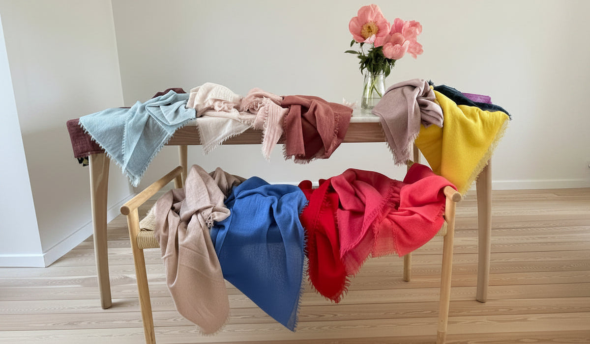 Colorful scarves draped over a wooden bench with flowers