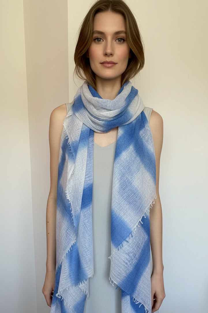 Mannequin wearing a blue and white plaid scarf in a room with wooden flooring.