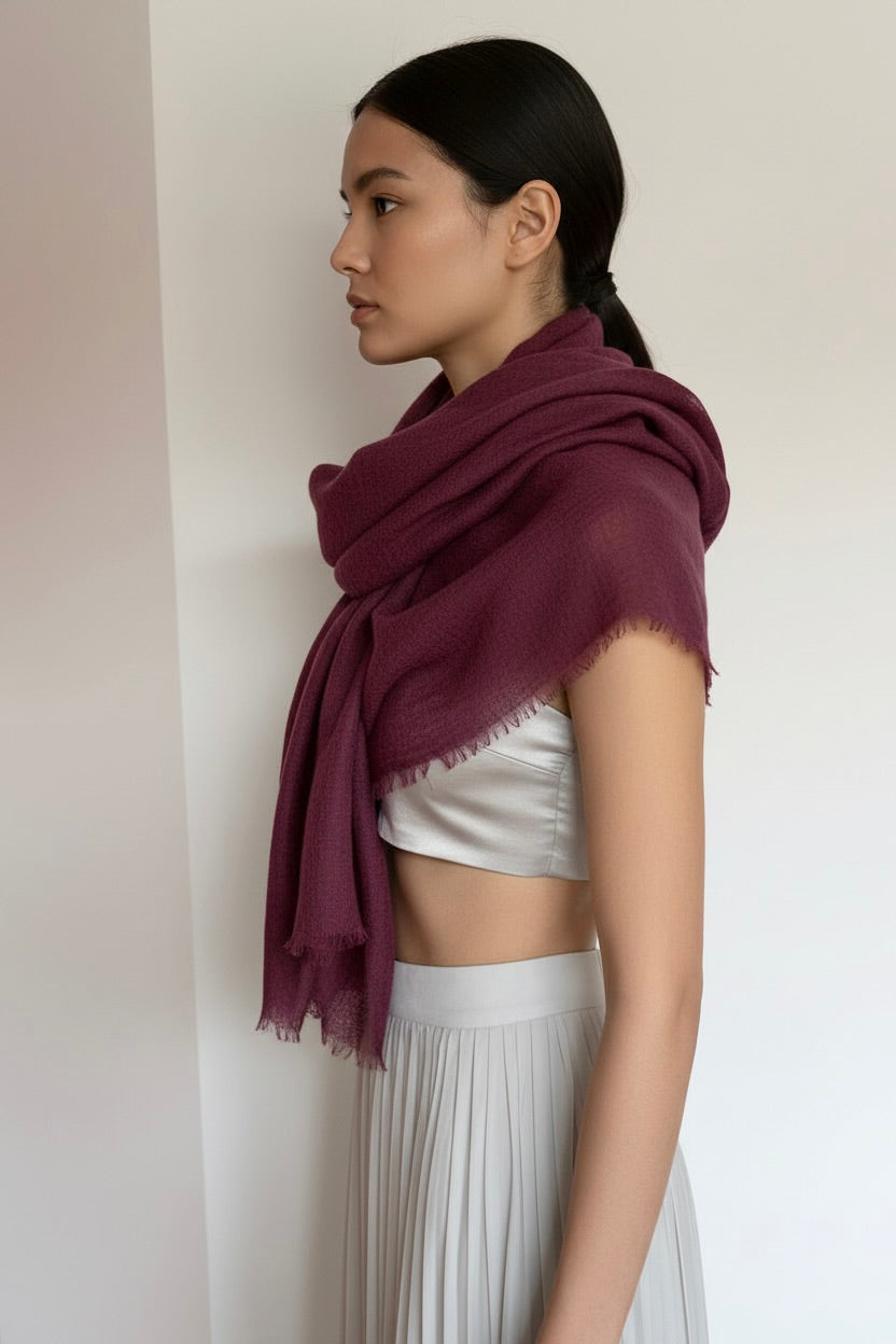 Woman wearing a maroon scarf and white top and skirt against a plain background