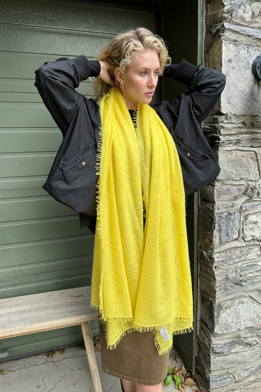 model wearing a yellow knit cashmere scarf with a dark coat in an outdoor setting