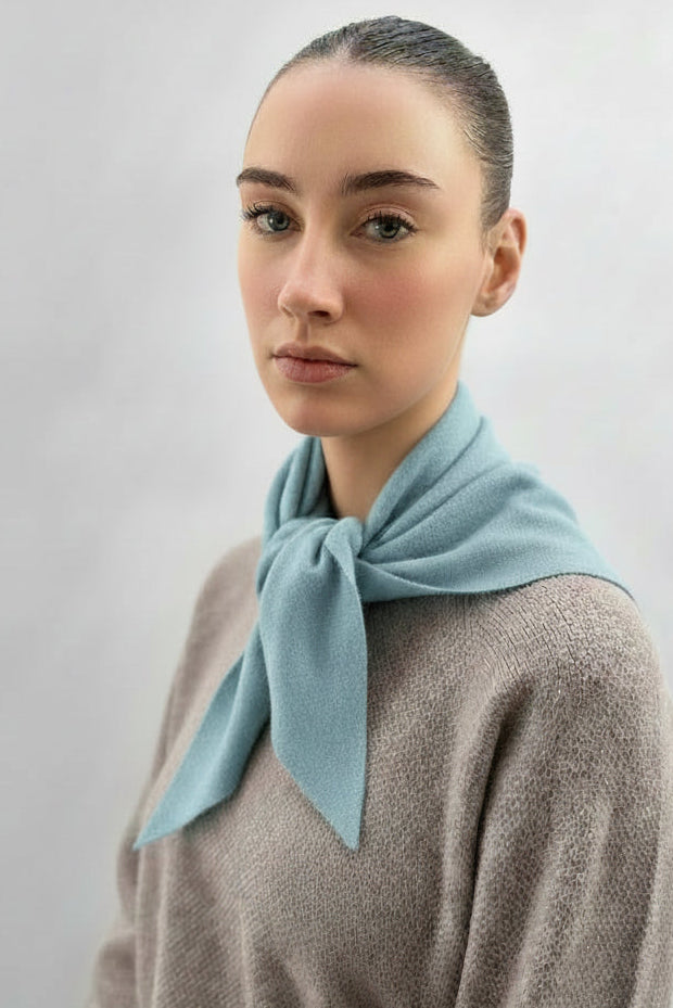Woman wearing a blue scarf around her neck against a plain background