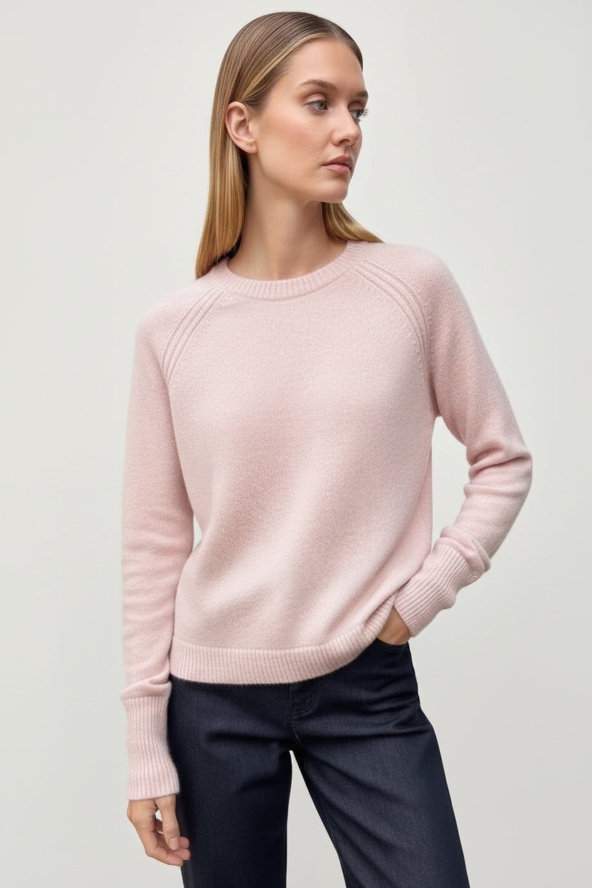 model in a pink cashmere sweater against a wall