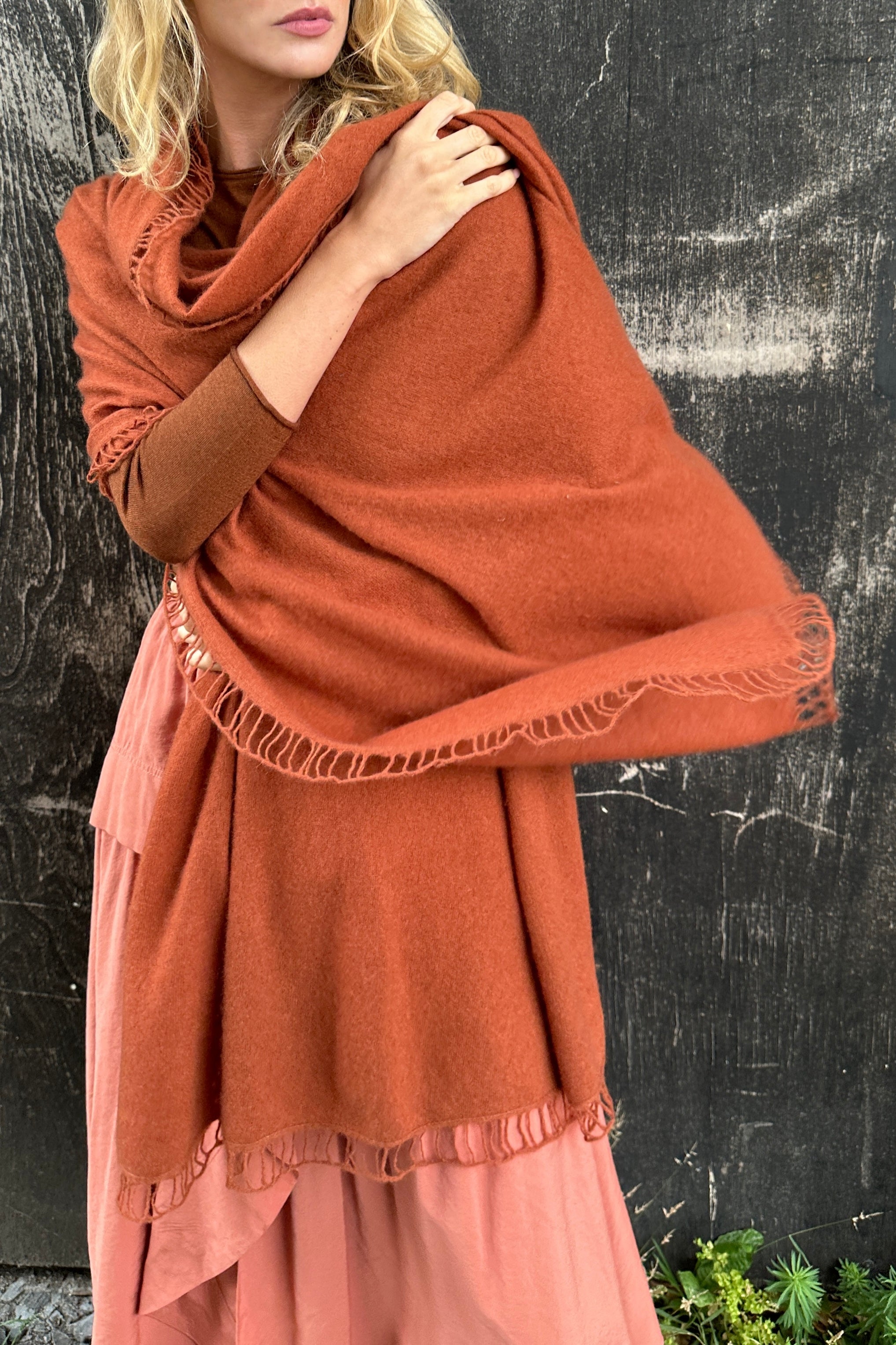 Person wearing a rust-colored scarf and dress against a black background
