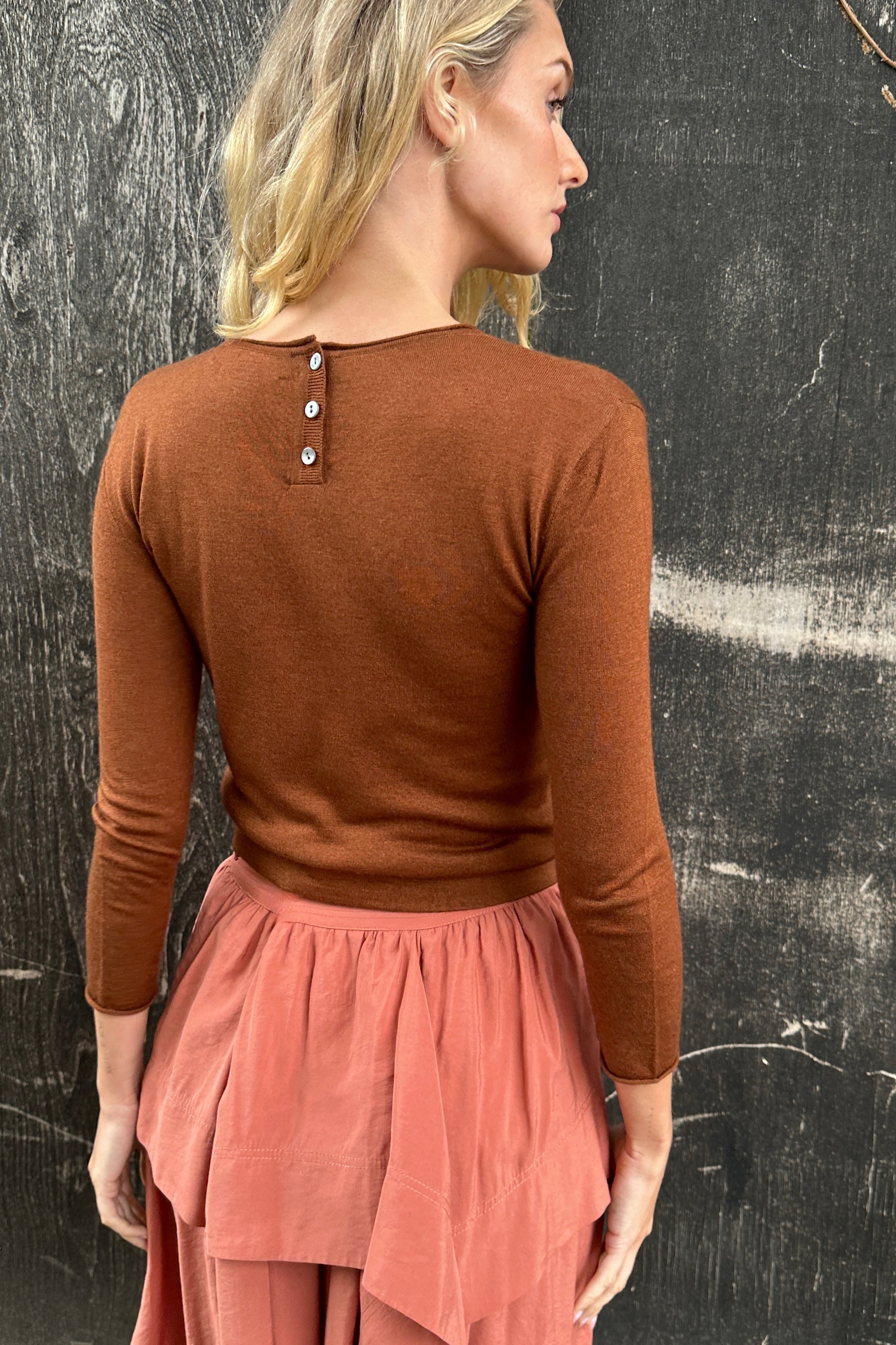 model wearing a rust brown cashmere silk top or sweater and pink skirt back view