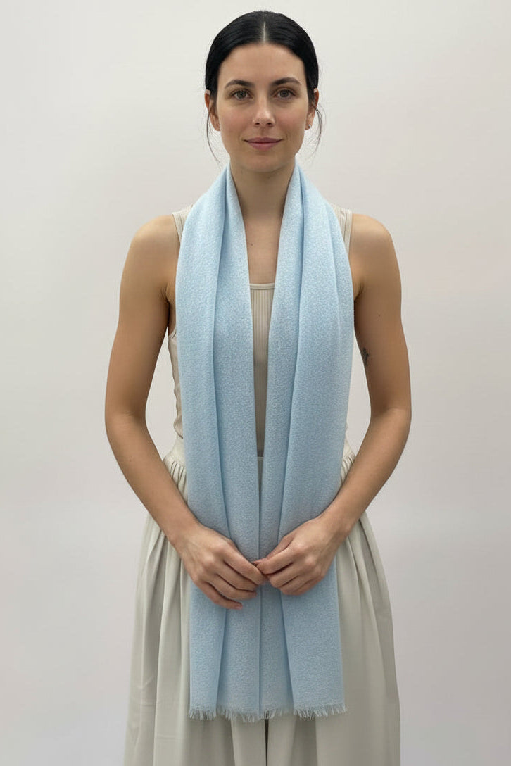 Woman wearing a light blue scarf in a neutral setting