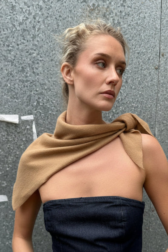 Person wearing a beige top and dark shorts on a gray pavement