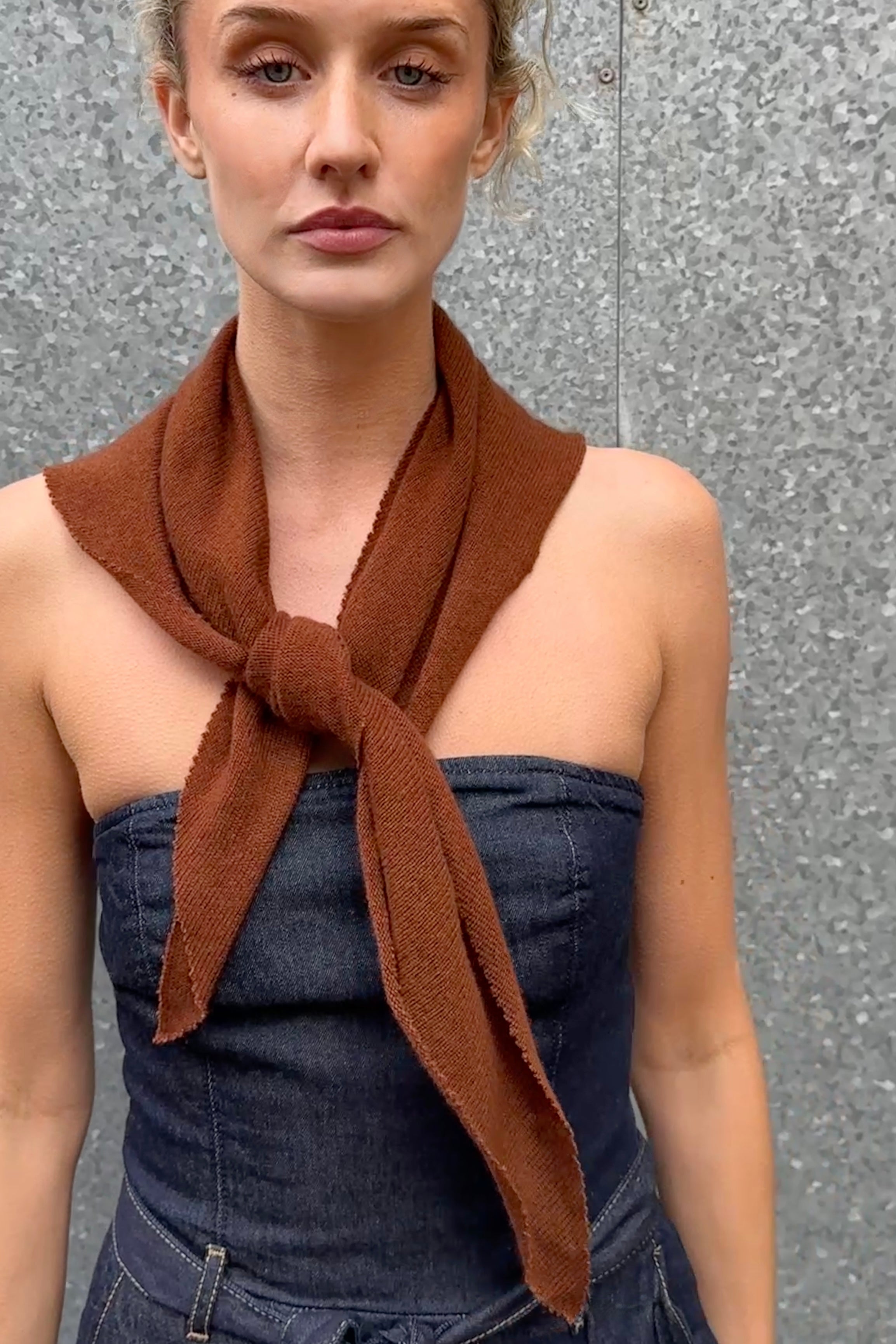 Woman wearing a brown scarf around her neck against a gray background doon cashmere