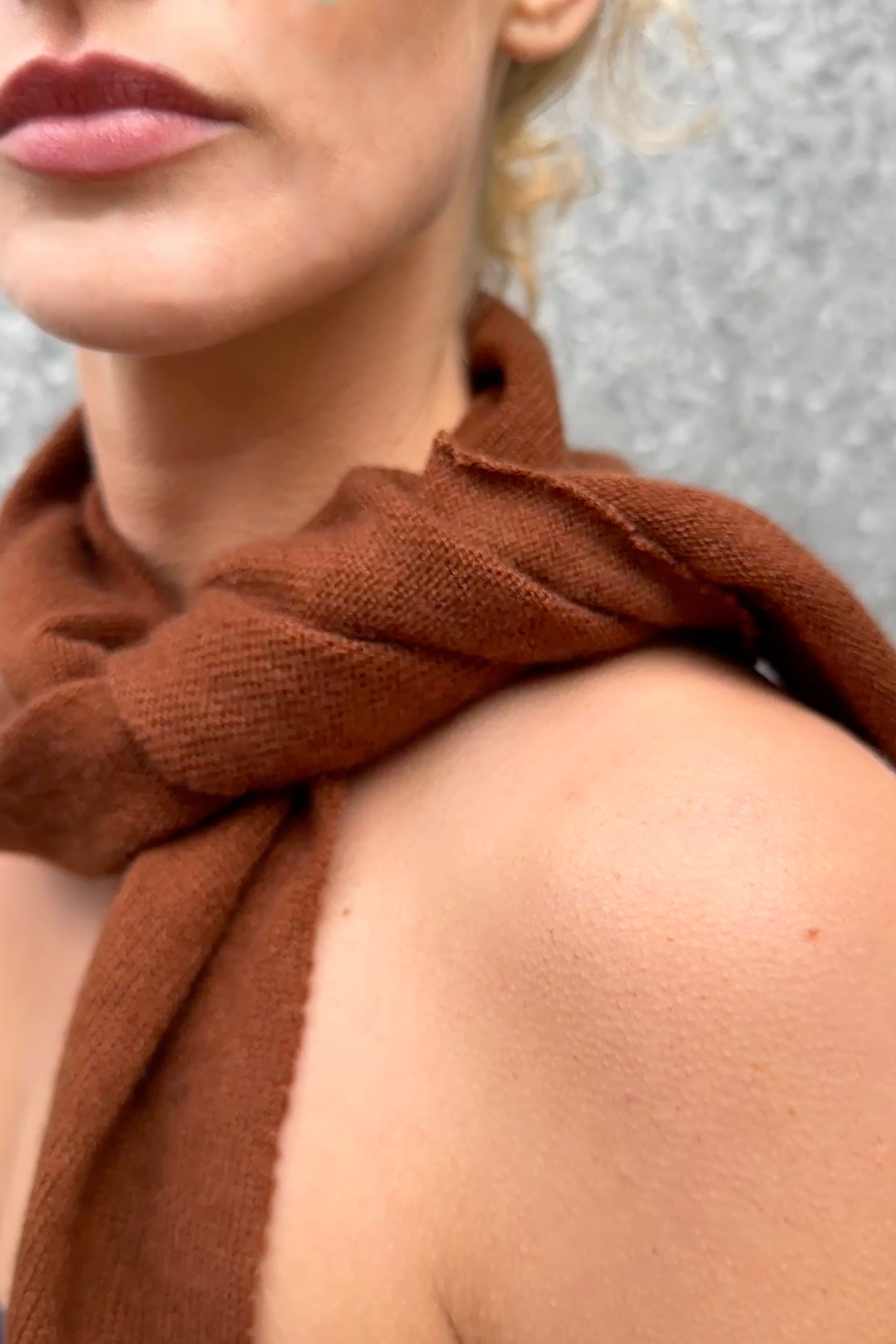 Close-up of a person wearing a doon cashmere brown scarf with a neutral background