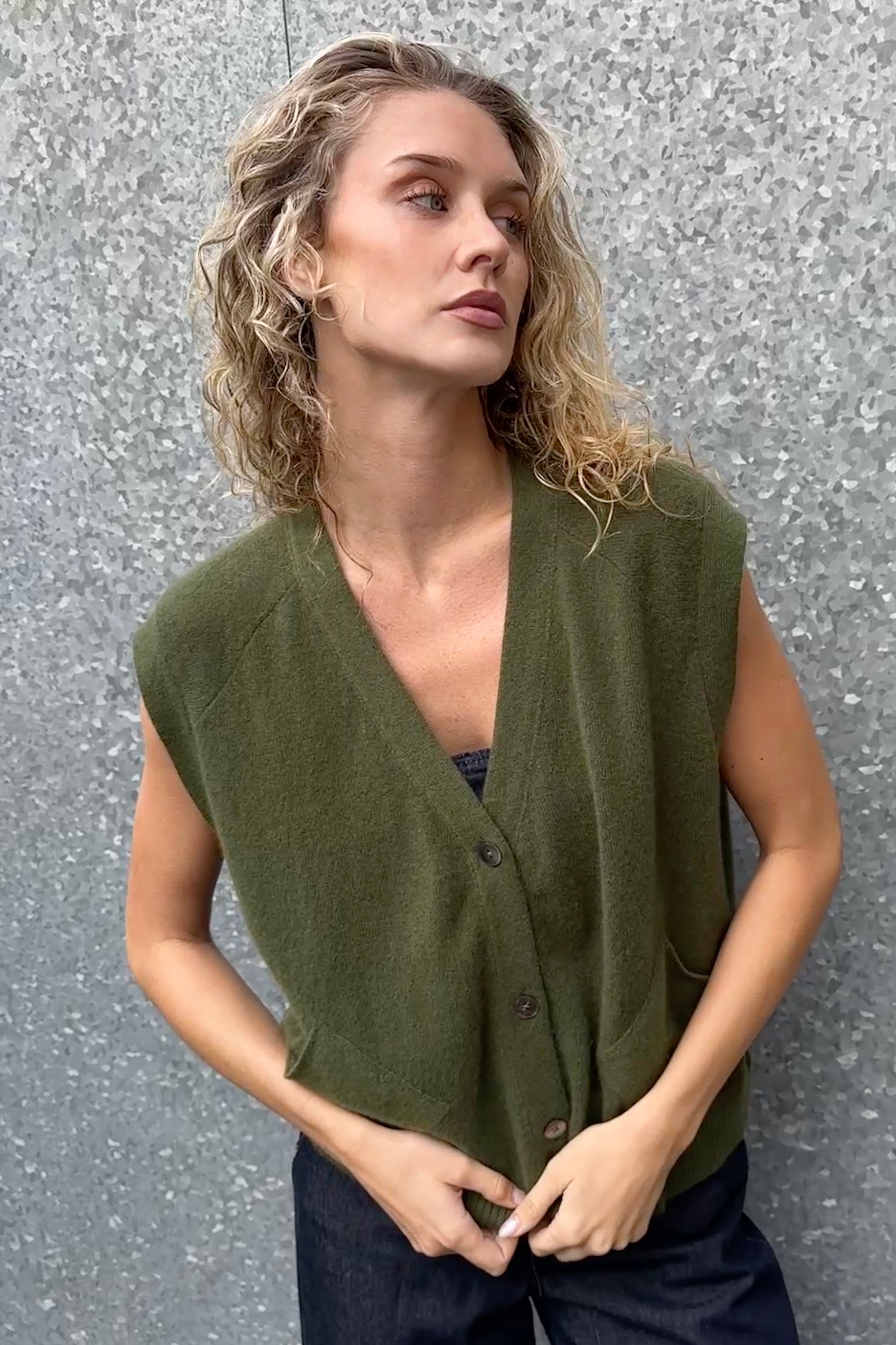 Woman wearing a green vest against a textured gray background