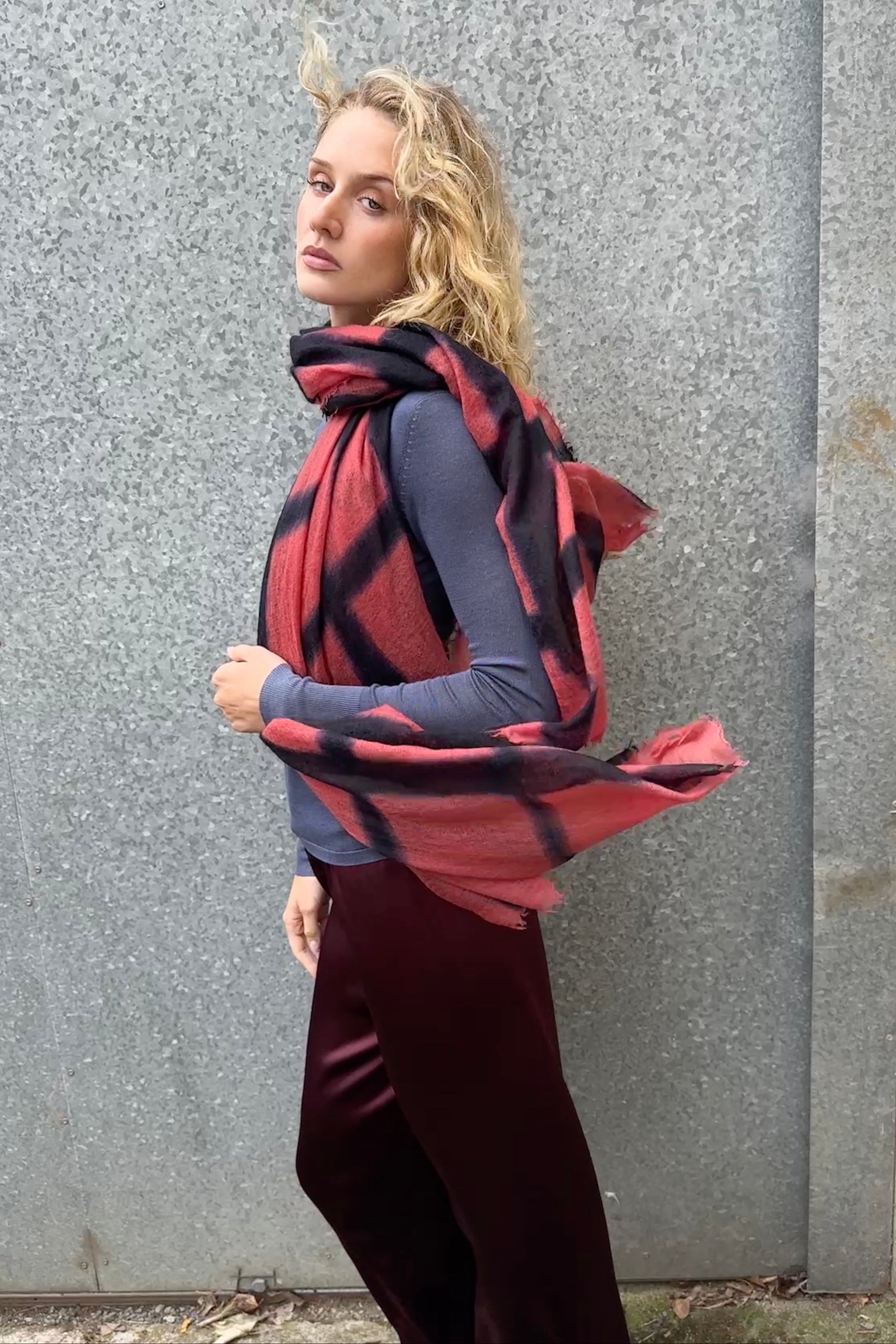 Woman wearing a red and black checkered scarf against a gray wall