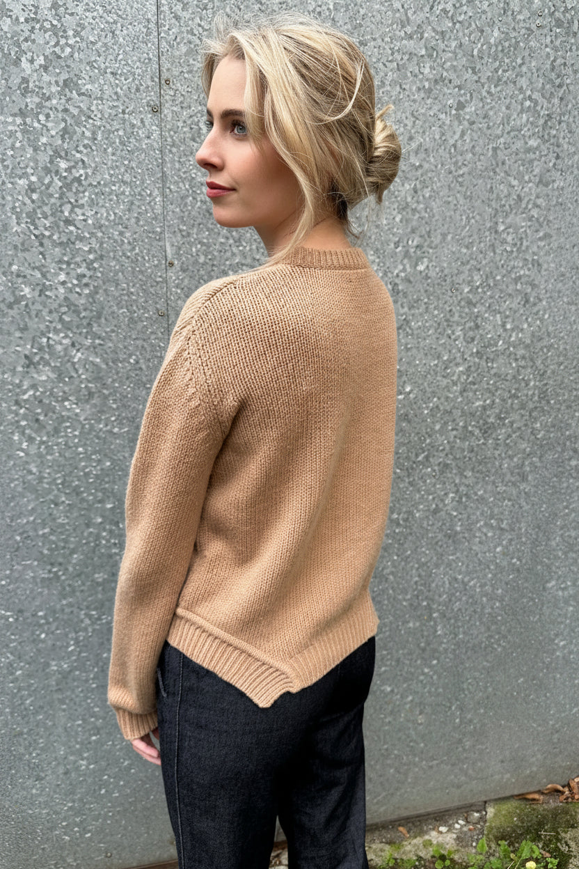 Person wearing a beige sweater and black pants on a road side view