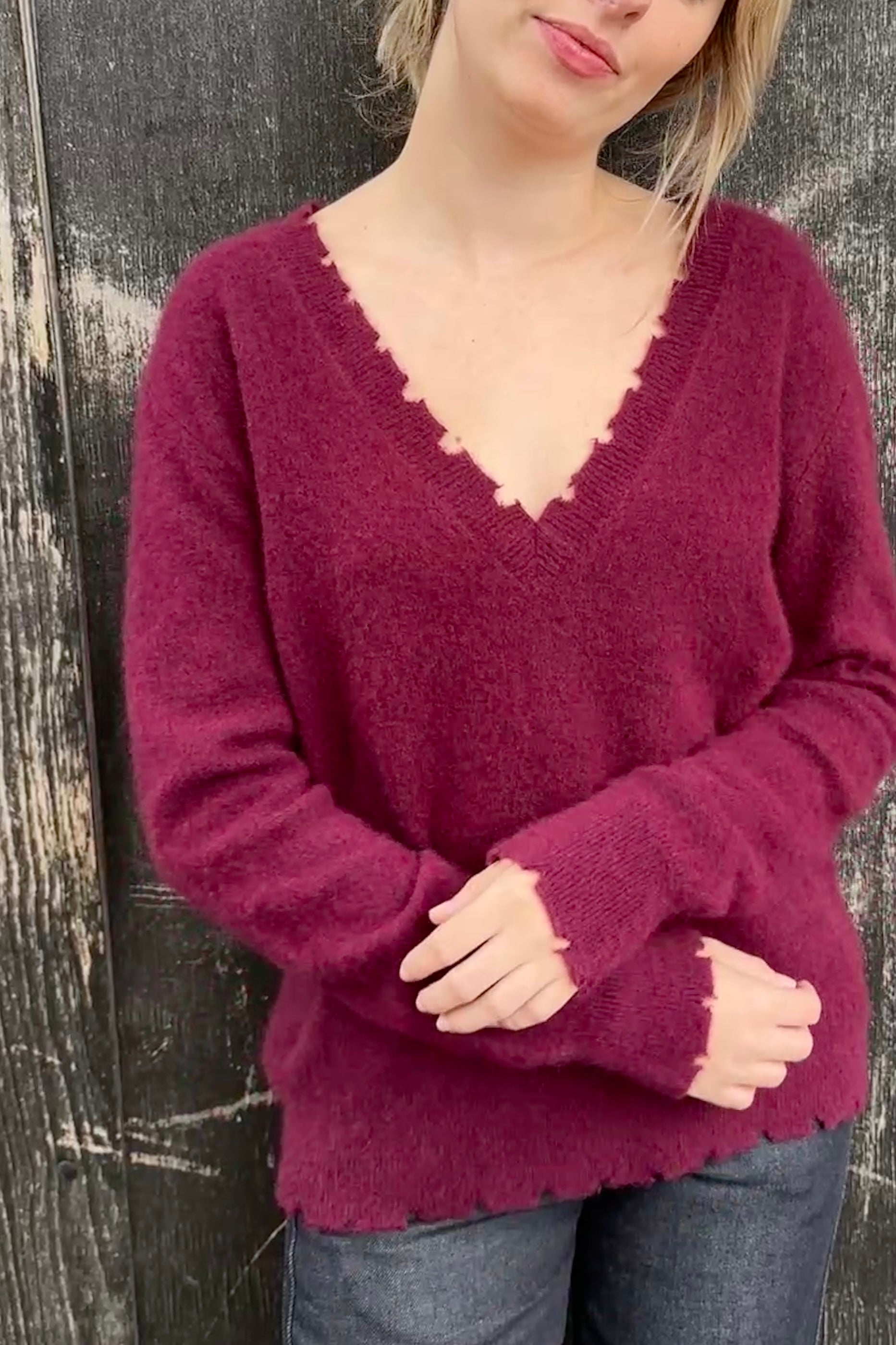 Person wearing a burgundy sweater against a wooden background