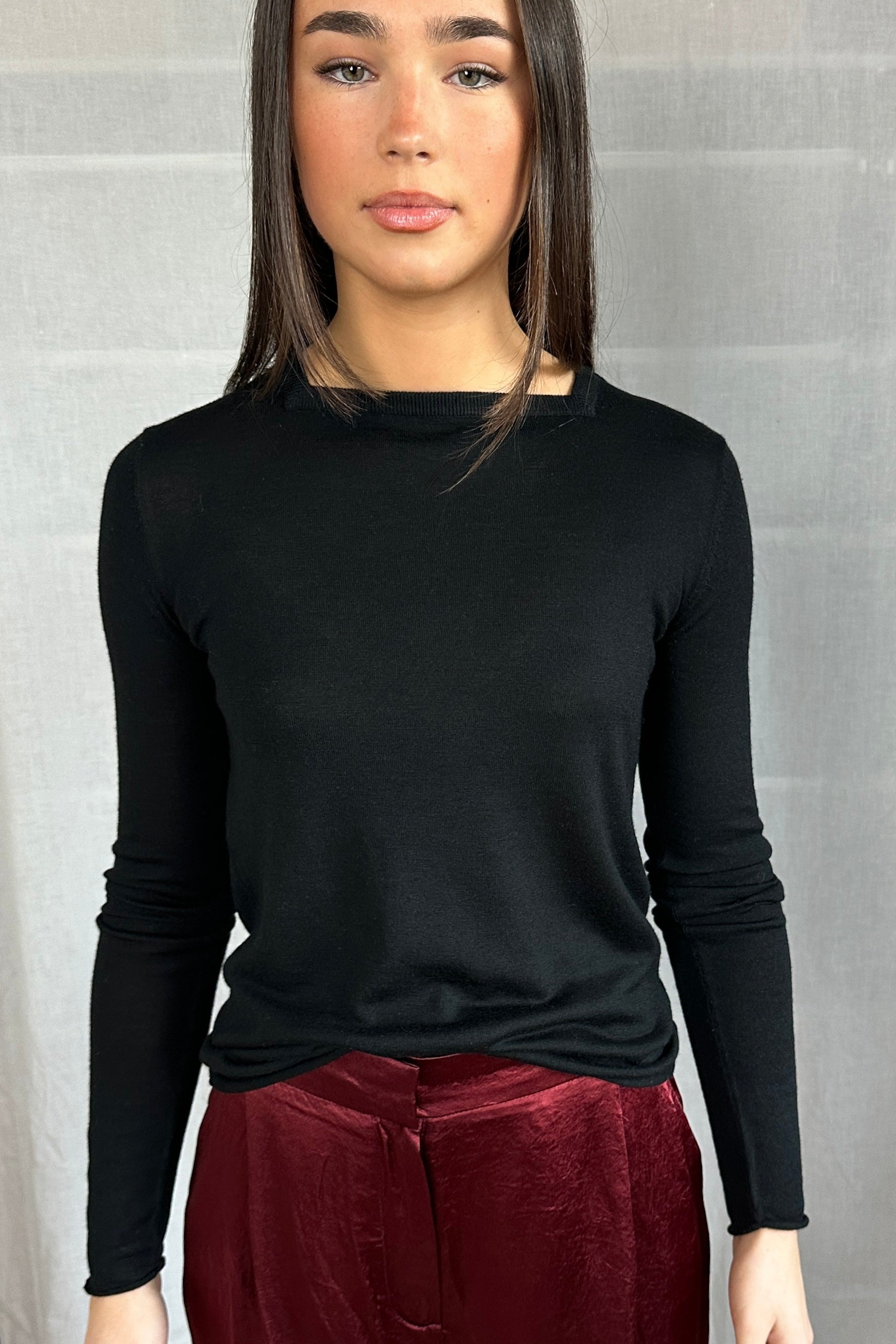 Model wearing a Lassa Square neck black long-sleeve top and maroon pants against a gray background