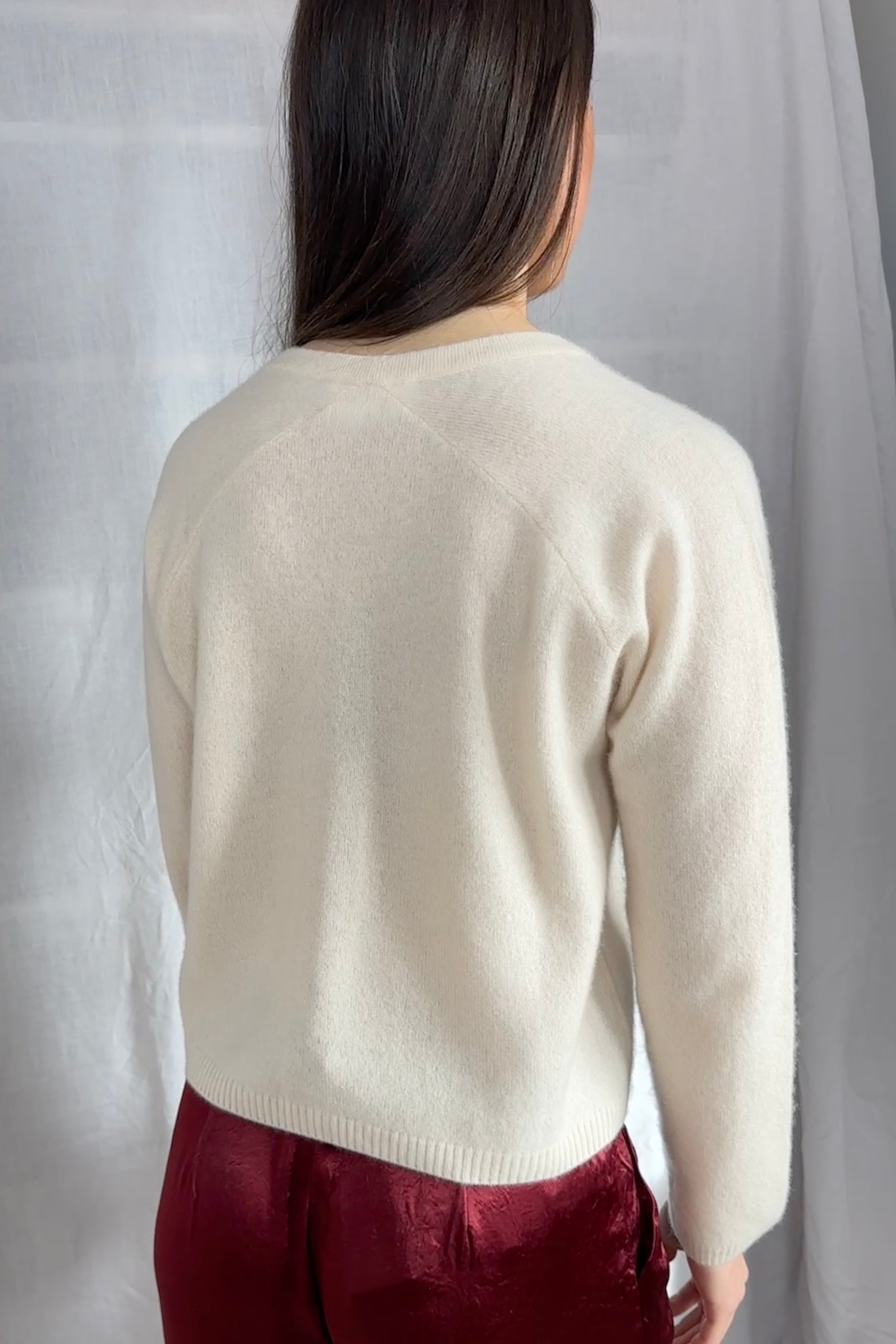model wearing a cream cashmere cardigan against a plain background ,zelia feather back view